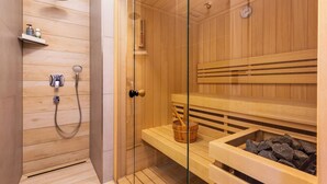 A sauna with wooden benches, a glass door, and a shower area with a handheld showerhead. - Cozy vacation home Elisa, house with fireplace, sauna, terrace, garden (Dranske-Lancken)