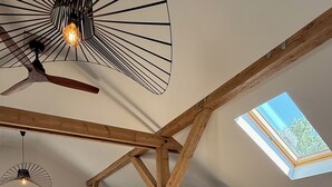 Een loft-achtige kamer met zichtbare houten balken, een dakraam, een bed, een slaapbank en een kamerkleed met dessin.