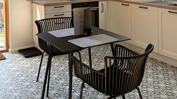 Een moderne keuken met dakraam, een eettafel met stoelen en een inbouwoven.