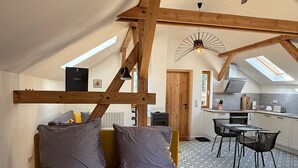 Een slaapkamer in een loft met een bed, een bureau en een keuken op de achtergrond.