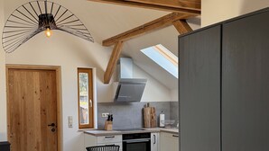 Een kleine keuken met een eethoek, met een houten plafond, dakraam en een moderne kookplaat.