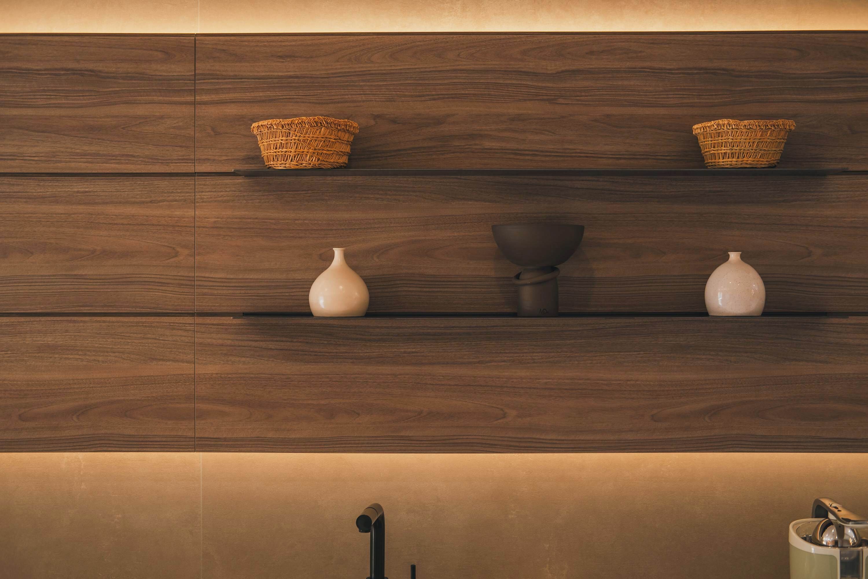 A wooden shelf with woven baskets and white vases.