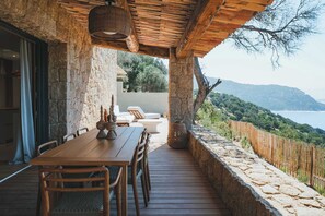 Eine Holzterrasse mit Tisch und Stühlen mit Blick auf eine gebirgige Landschaft.