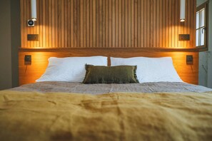 Ein Bett mit Holz-Kopfteil, zwei Wandleuchten und eine digitale Uhr.