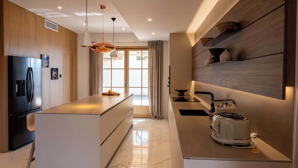 Una cocina moderna con una isla central, electrodomésticos integrados y vistas al exterior.