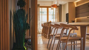 Una cocina moderna con armarios de madera, un ventanal grande y un comedor con sillas y mesa de madera.
