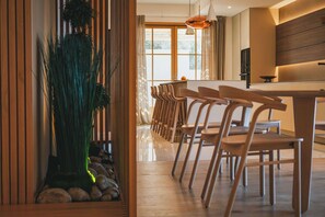 A modern kitchen with wooden cabinets, a large window, and a dining area with wooden chairs and a table.