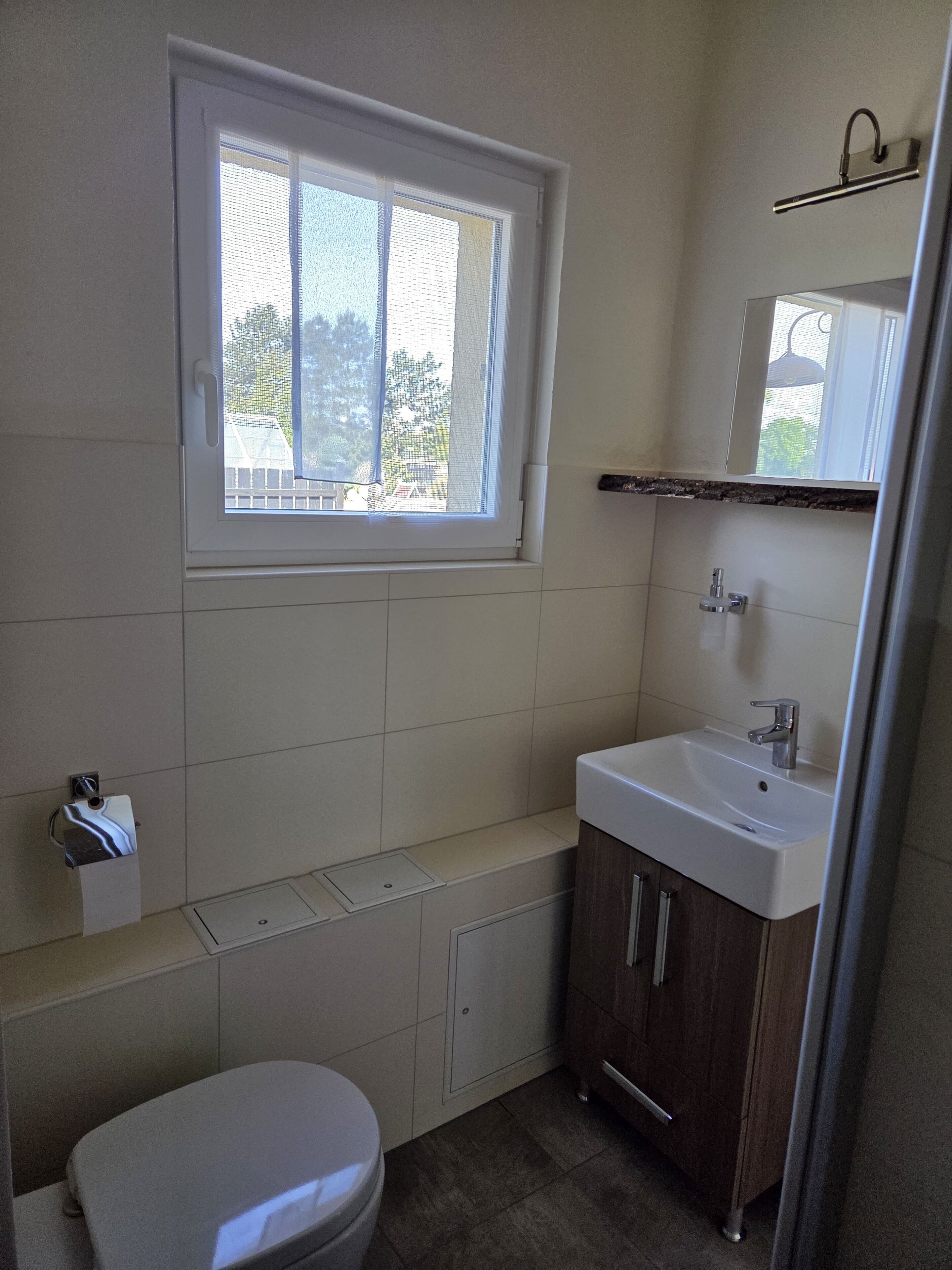 Ein kleines Badezimmer mit Toilette, Waschbecken und einem Fenster.