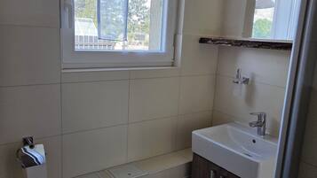 Ein kleines Badezimmer mit Toilette, Waschbecken und einem Fenster.