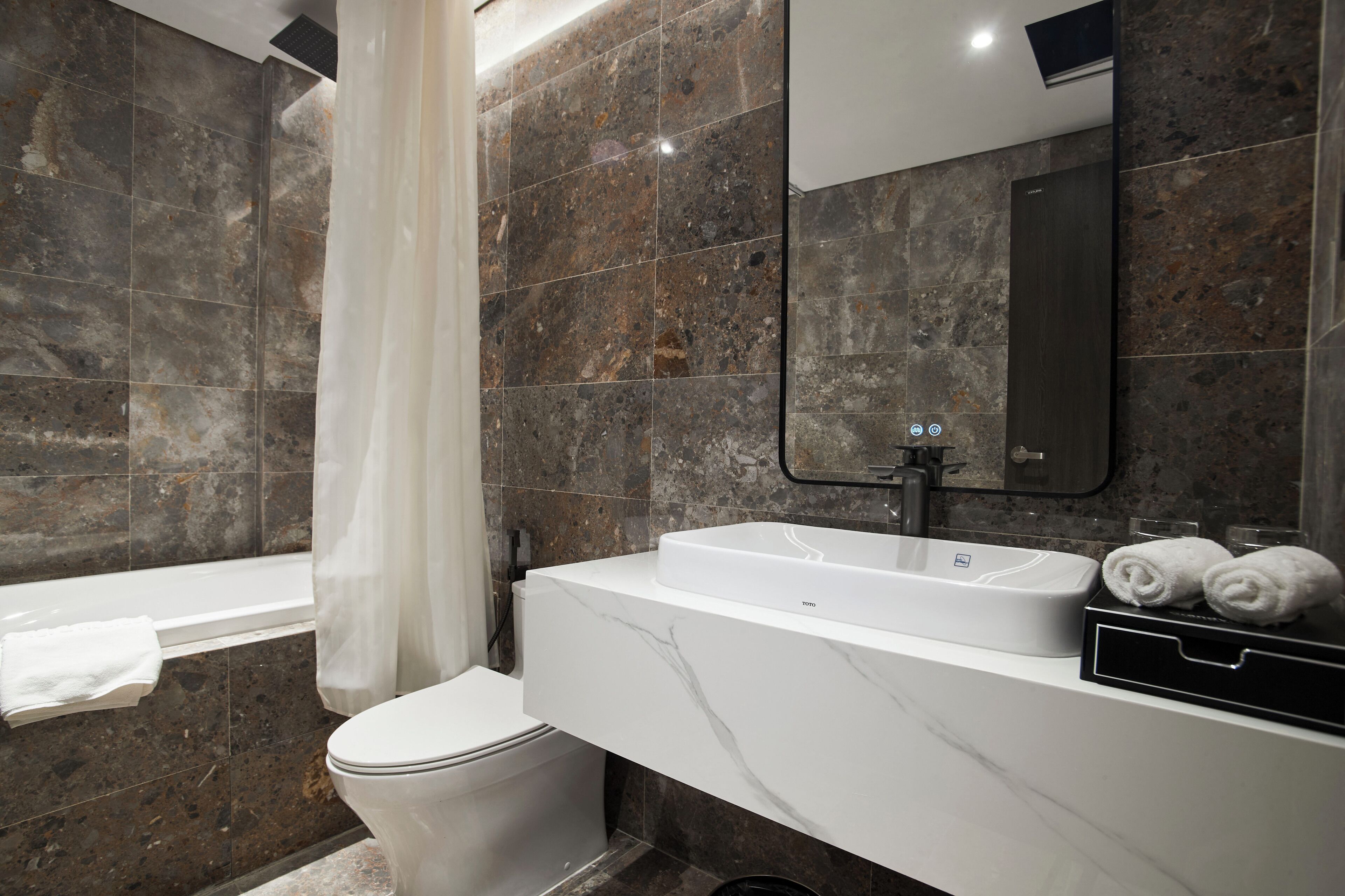 A modern bathroom with a marble sink, a toilet, and a shower area.