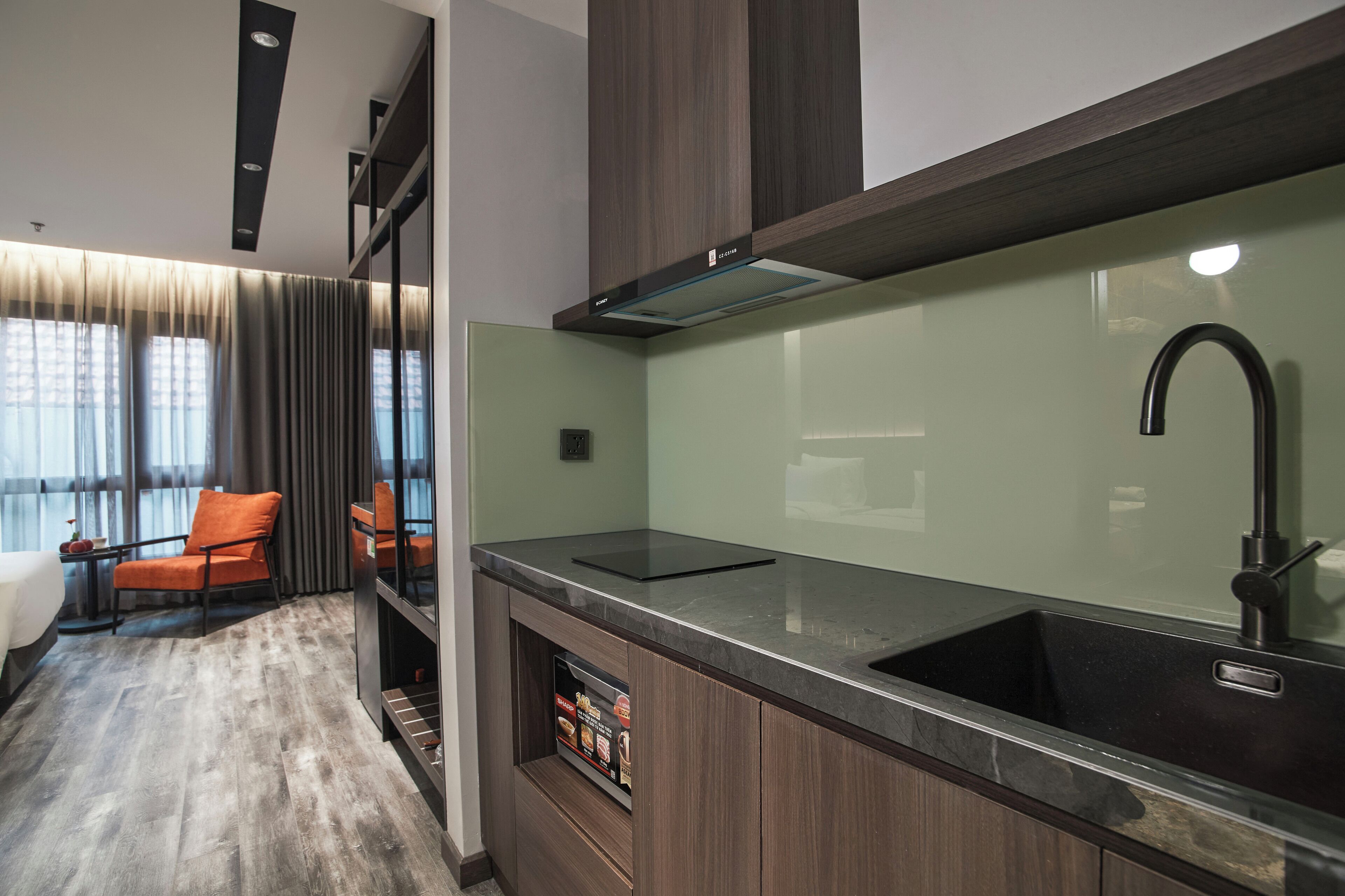 A modern kitchen with a dark countertop, a stainless steel sink, and a built-in oven.