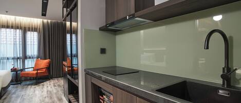 A modern kitchen with a dark countertop, a stainless steel sink, and a built-in oven.