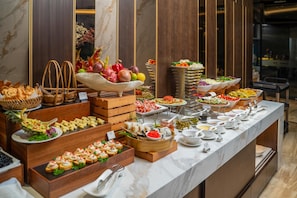 A buffet with various food items and utensils. - GrandView Hotel & Residence (Hanoi)