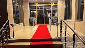 A hotel entrance with a red carpet leading to a reception desk, surrounded by glass doors and a tiled floor. - STARMAX CİTY HOTEL'S YALOVA (Yalova)