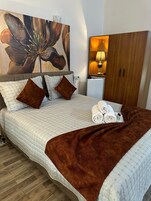 Una cama bien hecha con una manta marrón, una almohada y una toalla doblada sobre la cama.