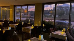A restaurant with tables covered in patterned tablecloths, chairs, and ambient lighting. - STARMAX CİTY HOTEL'S YALOVA (Yalova)