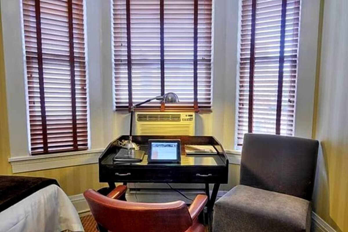 A room with a desk, two chairs, and a window with blinds.