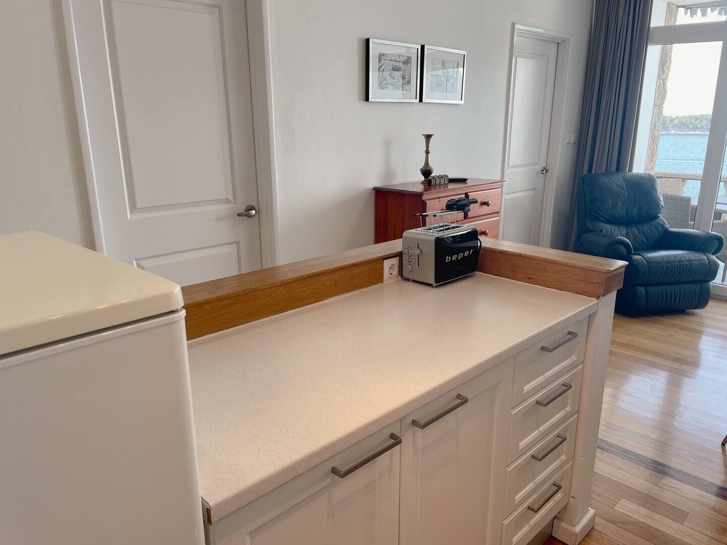 A kitchen with a toaster, cabinets, and a view of the sea.