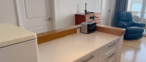 A kitchen with a toaster, cabinets, and a view of the sea.