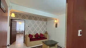 A living room with a sofa, a small table, patterned wallpaper, and a door labeled "Valley Suite". - The Kaizer Valley Hotel (Kurseong)