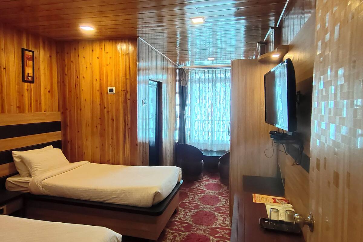 A wooden room with a bed, a television, and a door.