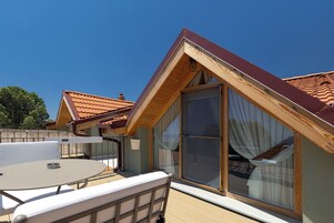 Una cabaña con techo de madera, un balcón, una mesa y una silla.