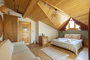 Un dormitorio acogedor con techo de madera, una cama con colcha estampada, un pequeño armario de madera y una lámpara de mimbre.