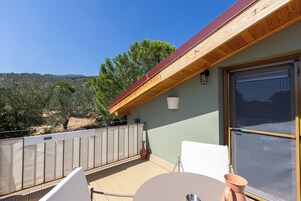 Un balcón con mesa, sillas y vistas a un paisaje montañoso.