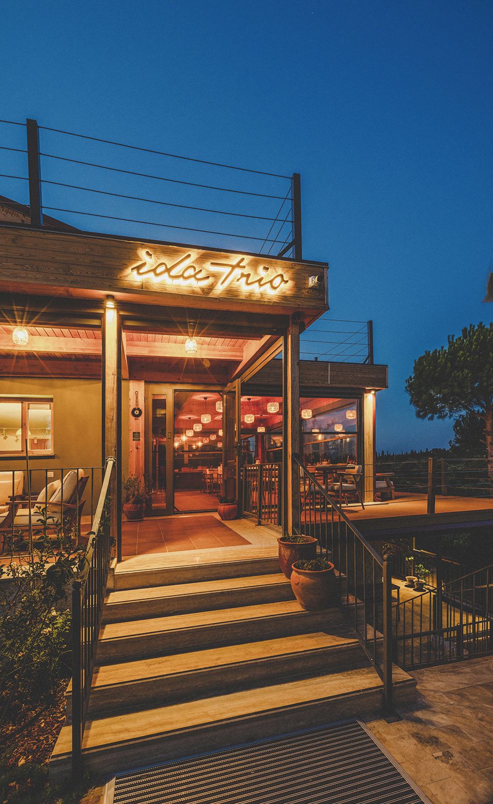 A restaurant named "Iola Trio" with outdoor seating and a staircase leading to the entrance.
