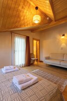 Una habitación acogedora con techo de madera, un sofá, una mesita pequeña y dos camas con toallas.