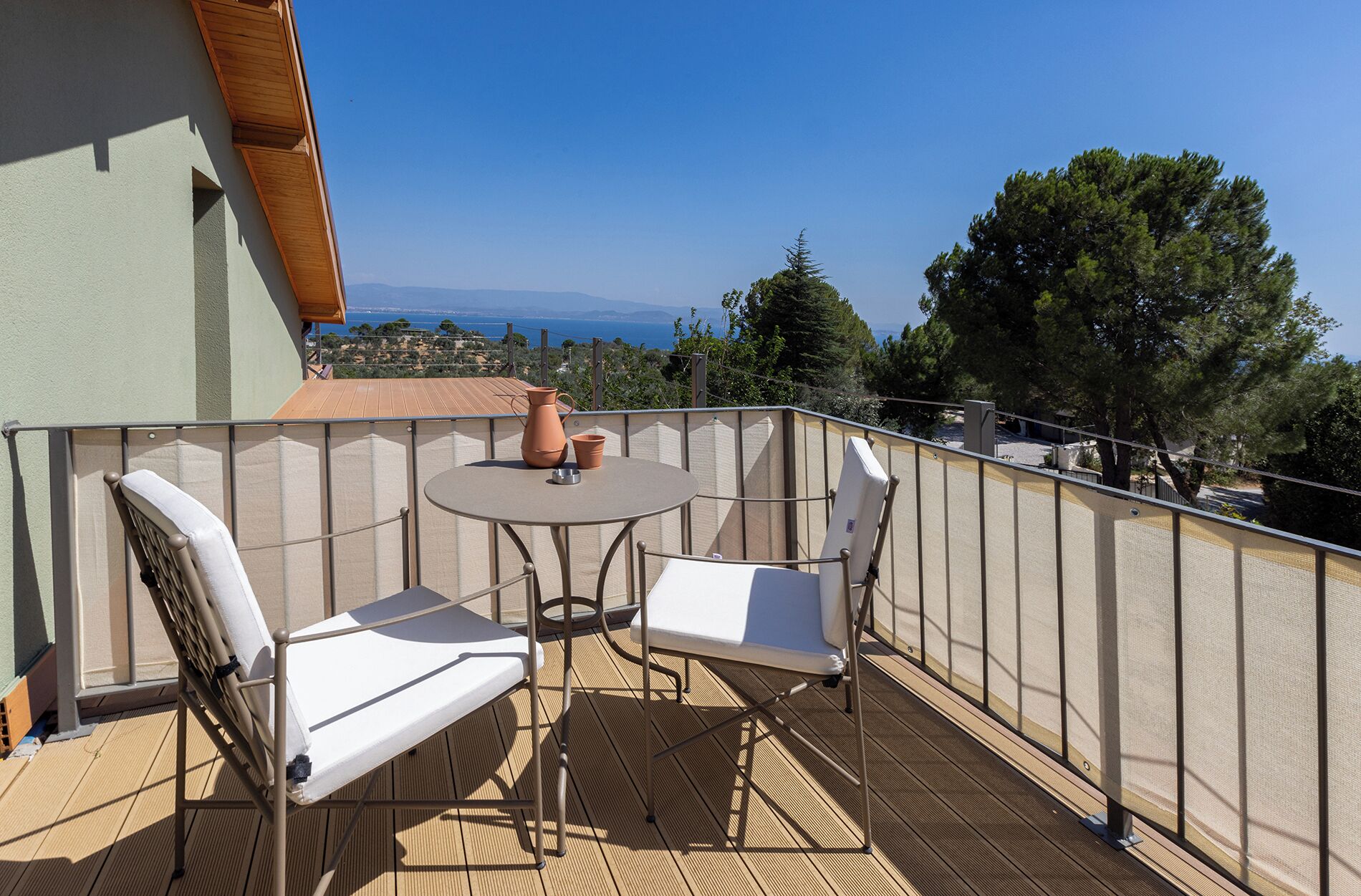 A balcony with a table, two chairs, and a potted plant.