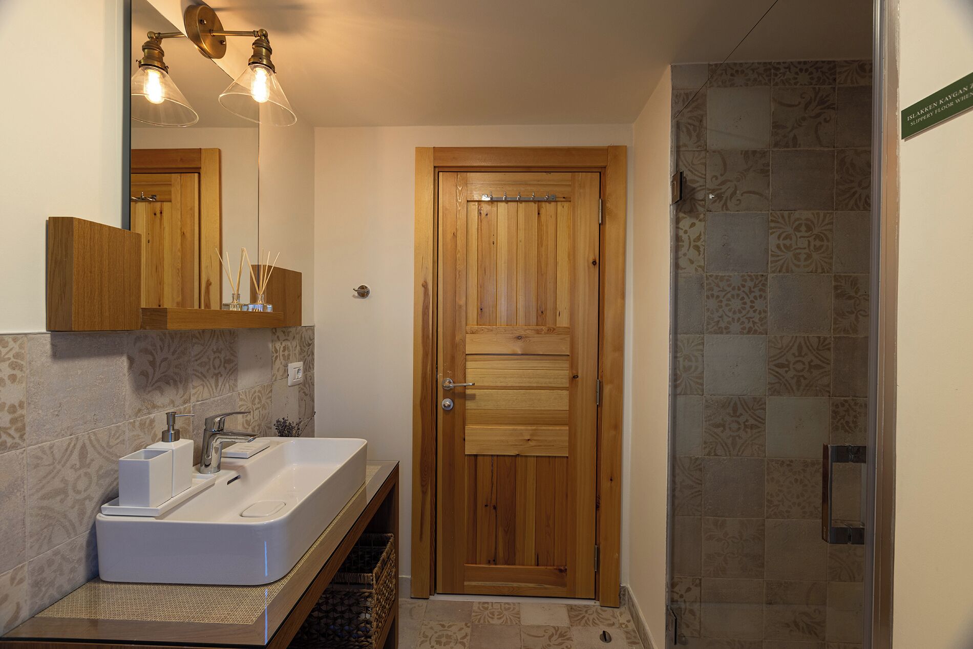 A bathroom with a wooden door, a white sink, and a shower area.