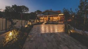 A two-story house with a covered patio and a well-lit entrance. - Ida Trio (Edremit)