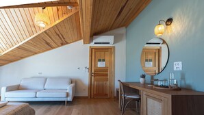 A cozy room with a wooden ceiling, a sofa, a desk with a mirror, and a small cabinet. - Ida Trio (Edremit)