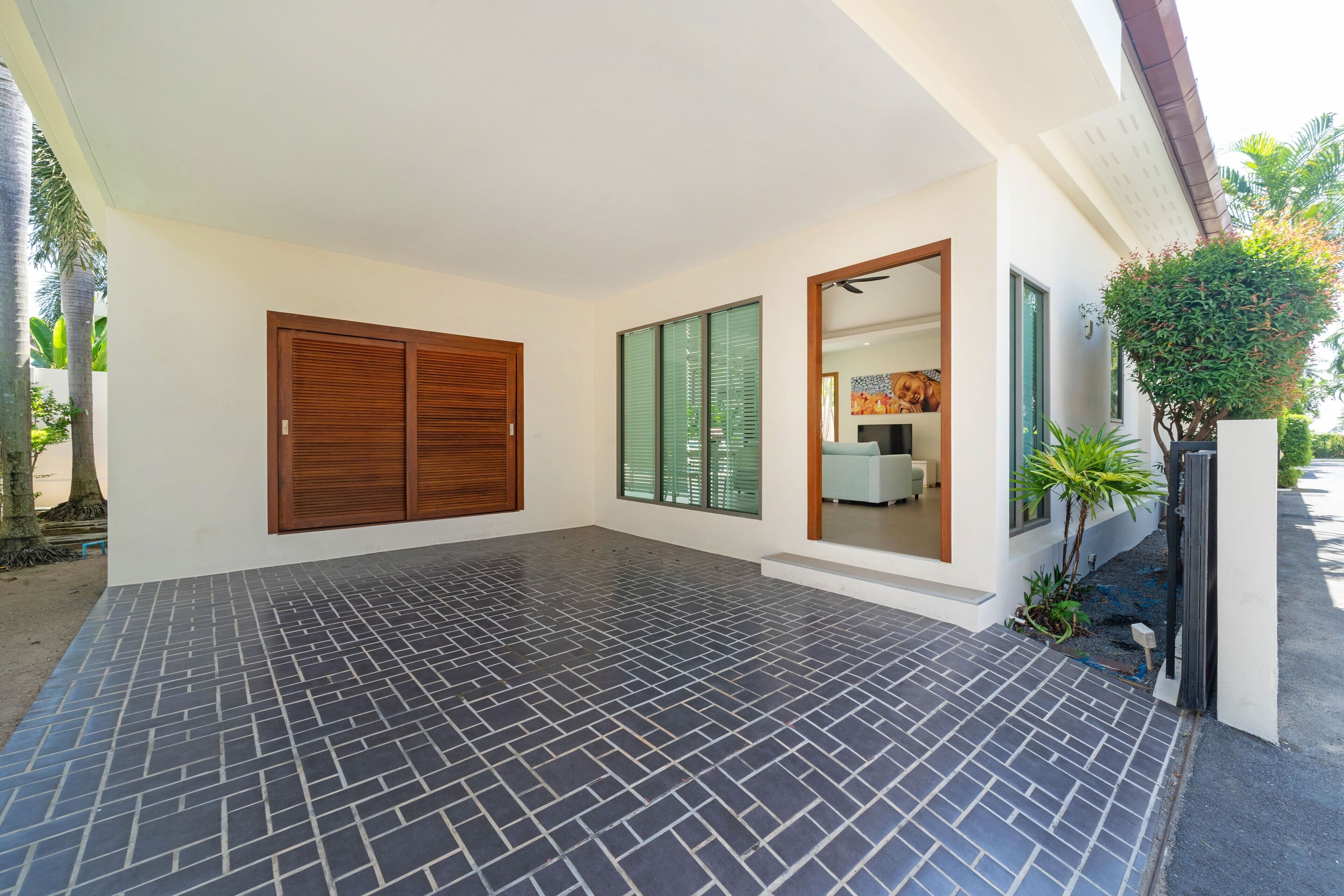 A spacious indoor area with a tiled floor, a wooden door, and a large window with green shutters.