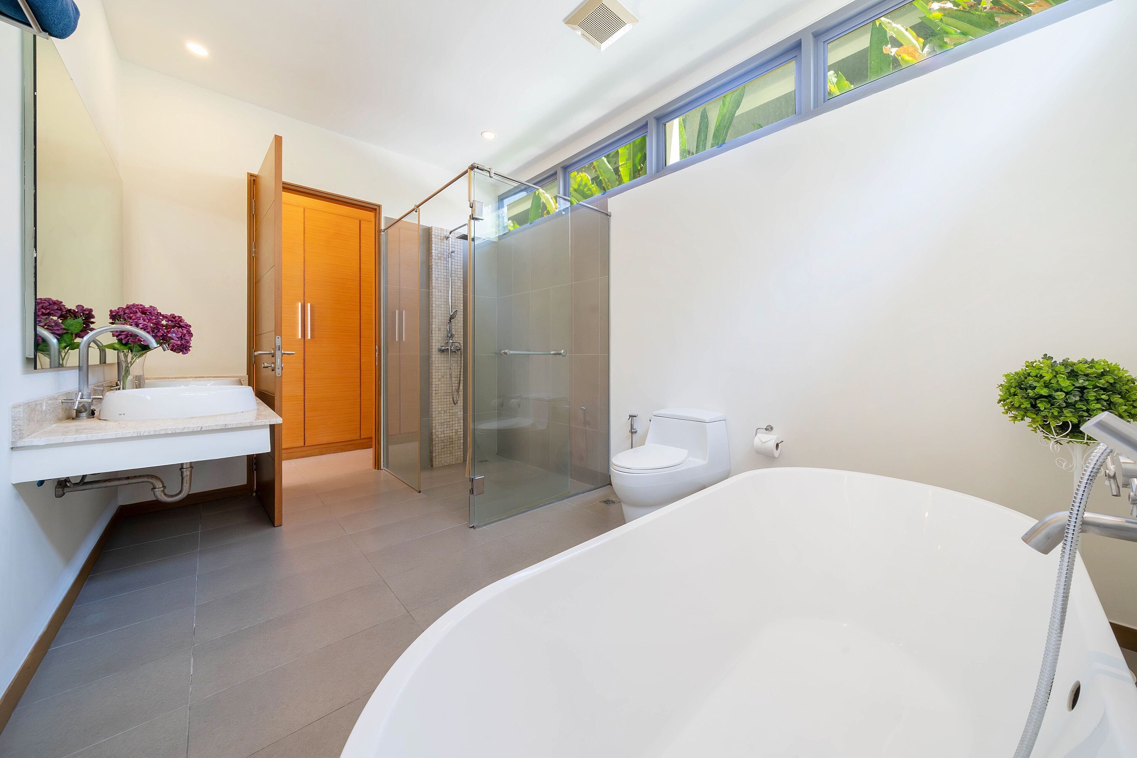 A modern bathroom with a large bathtub, a glass-enclosed shower, a toilet, and a vanity with a mirror and sink.