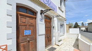 Un edificio con dos puertas de madera, un letrero que dice "Maison" y un acceso empedrado de piedra.