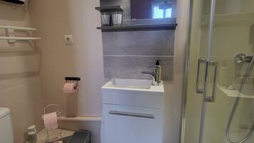 Un baño con inodoro, lavamanos, espejo, ducha y toallero.