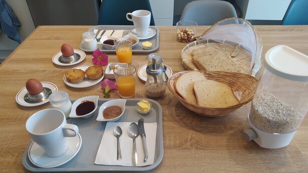 Bandeja de desayuno con huevos, tostadas, jugo y salsas sobre una mesa de madera en una habitación de hotel.