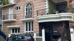 Een tweelaags huis met een balkon en een trap, en een auto geparkeerd ervoor.
