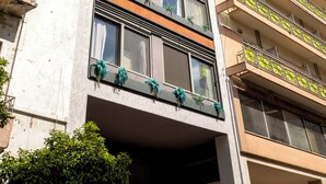 Ein mehrgeschossiges Gebäude mit Balkonen, großen Fenstern und blauem Himmel.
