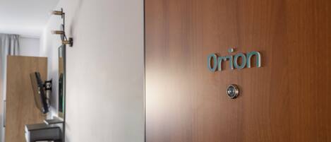 Une porte en bois sur laquelle est inscrit le mot « Orion » en lettres métalliques.