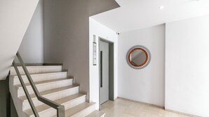 Ein modernes Interieur mit Treppe, Aufzug und einem runden Spiegel an der Wand.