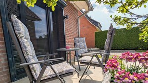 An outdoor seating area with two chairs and a table, a brick wall, and a hedge in the background. - Comfortable, fully equipped apartments, near Geesthacht  (Geesthacht)