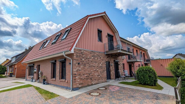 A two-story brick building with a sloped roof and a balcony on the second floor. - Comfortable, fully equipped apartments, near Geesthacht  (Geesthacht)