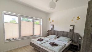 A modern bedroom with a wooden bed frame, two bedside tables, and a large window with blinds. - Comfortable, fully equipped apartments, near Geesthacht  (Geesthacht)