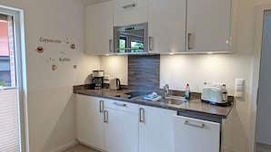 A modern kitchen with white cabinets, a built-in oven, a coffee maker, a toaster, and a sink. - Comfortable, fully equipped apartments, near Geesthacht  (Geesthacht)