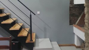 A staircase with a modern design, a wall-mounted clock, and a stone accent wall.