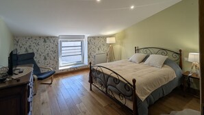 Une chambre à coucher avec un lit, un bureau, une chaise, une fenêtre et une lampe.