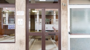 Une entrée d’immeuble avec une porte marron et un panneau de verre.